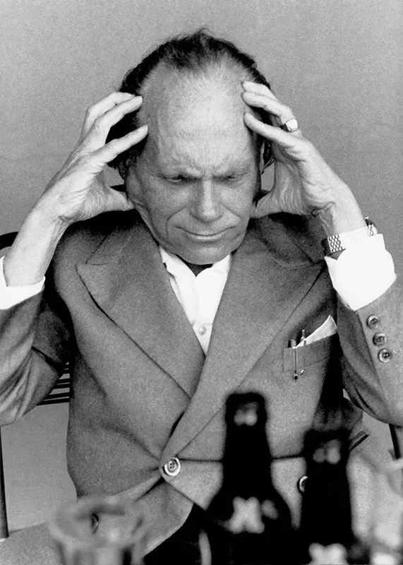 Fotografia dell'artista Romano Zaniol, elegantemente vestito con le mani tra i capelli in un momento di grande concentrazione.