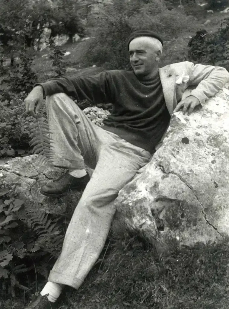 Fotografia di un giovane Giovanni Comisso, adagiato su di una roccia in montagna.